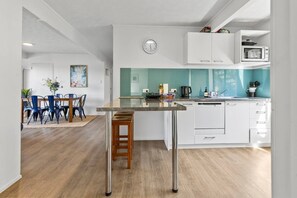 A modern kitchen with a central island, white cabinetry, and a teal backsplash. - Marina Views Apartment 2 - downstairs apartment (Taupō)
