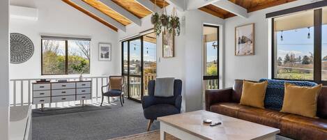 Un'ampia zona giorno con soffitto in legno, un divano, un tavolino da caffè e vista panoramica attraverso ampie finestre.