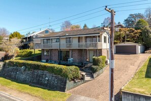 Ein zweigeschossiges Wohnhaus mit Veranda, Garage und gepflegtem Rasen.