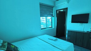 A bedroom with a single bed, a window with blinds, a flat-screen TV mounted on the wall, and a door leading to another room. - HOANG LONG 1 HOTEL (Hanoi)