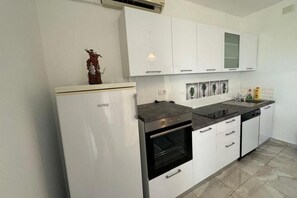Eine moderne Küche mit weißen Schränken, einem eingebauten Backofen und einer Arbeitsfläche mit Spüle.