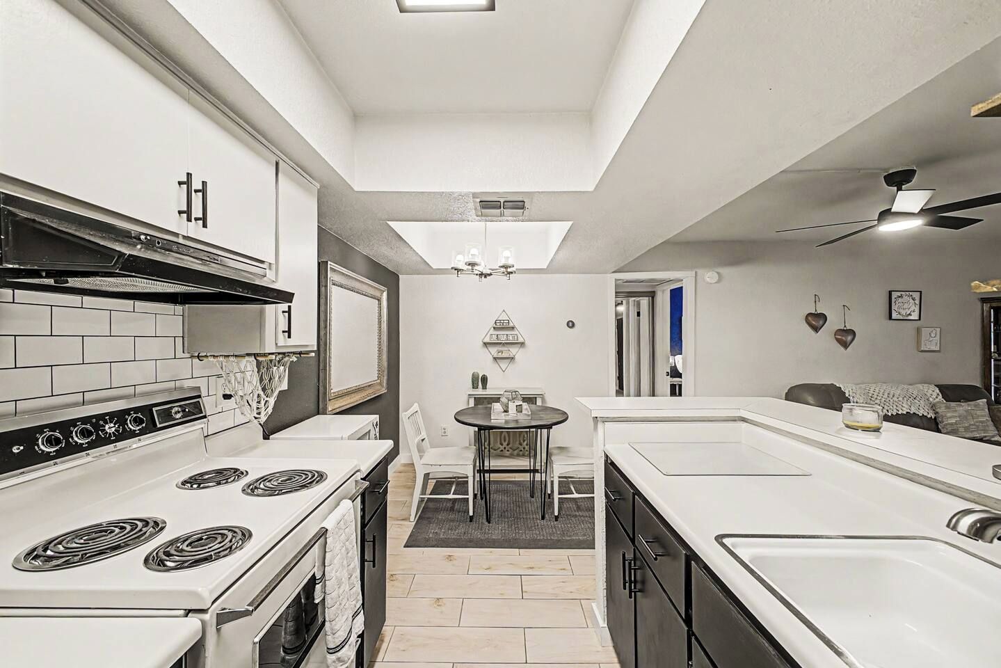 A compact kitchen with a central island, a dining table, and a ceiling fan.