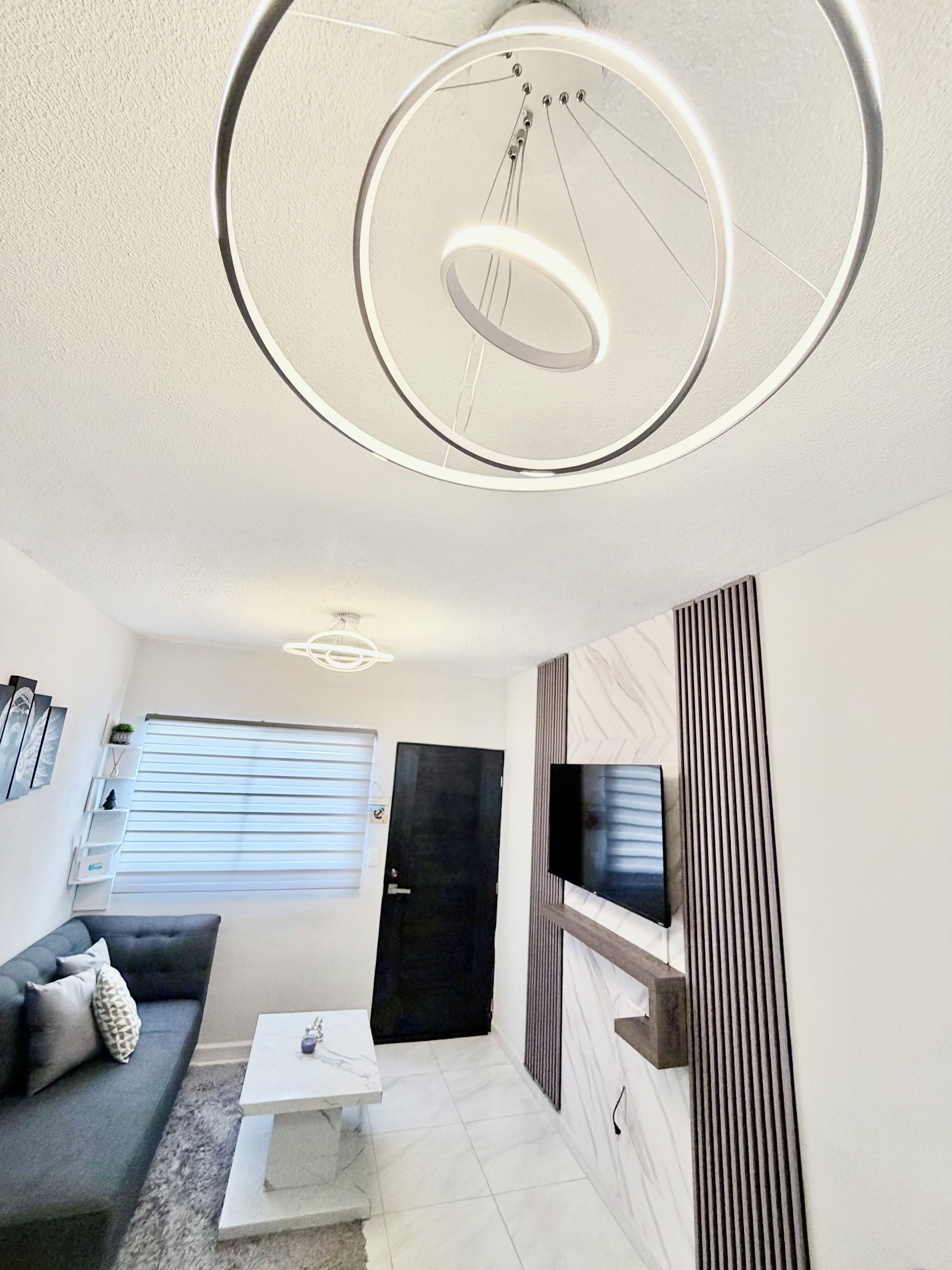 Ein modernes Wohnzimmer mit einer Couch, einem Couchtisch und einem an der Wand befestigten Fernseher.