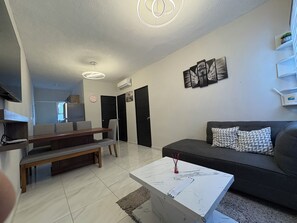 A modern living room with a sofa, a coffee table, and a dining area with chairs and a bench. - Acapulco shines! Beautiful apartment. Just 15 minutes from Puerto Márquez and P. Diamante (Acapulco de Juárez)