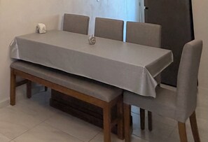 A dining table with a grey tablecloth, four chairs, and a bench. - Acapulco shines! Beautiful apartment. Just 15 minutes from Puerto Márquez and P. Diamante (Acapulco de Juárez)
