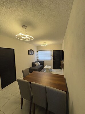 A compact living space with a dining area, a sofa, a small table, and a ceiling light fixture. - Acapulco shines! Beautiful apartment. Just 15 minutes from Puerto Márquez and P. Diamante (Acapulco de Juárez)