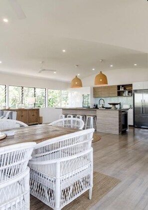 A modern kitchen with white cabinetry, a central island, and pendant lighting. - Luxe Sunshine Beach House - 30m to Beach! (Sunshine Beach)
