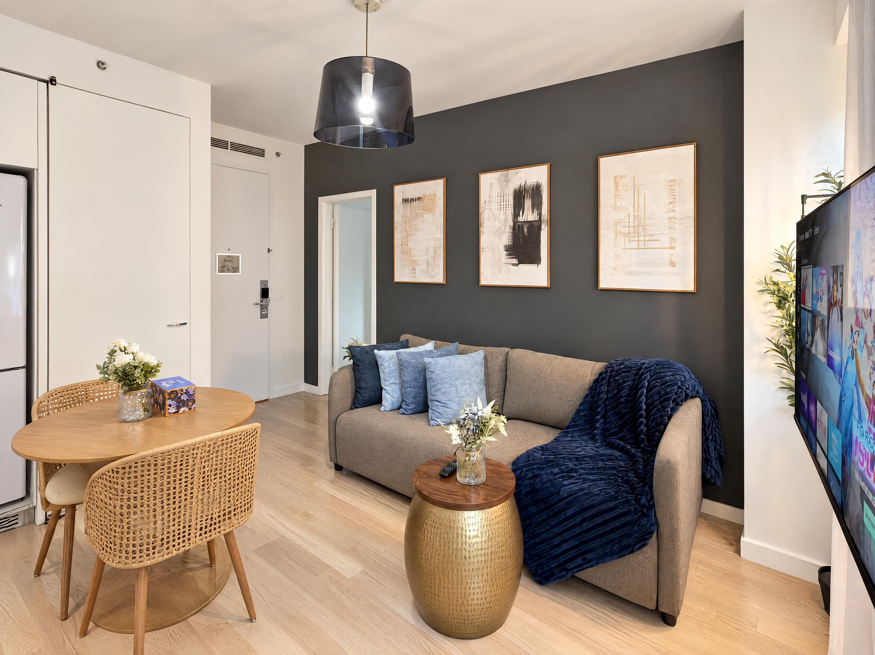 Una sala de estar moderna con un sofá, una mesa de comedor con sillas y una pantalla de televisión grande.