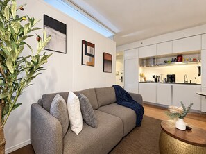 A modern living room with a grey sofa, a coffee table, and a large plant.