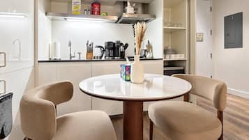A modern kitchen with a round table, two chairs, and various kitchen appliances.