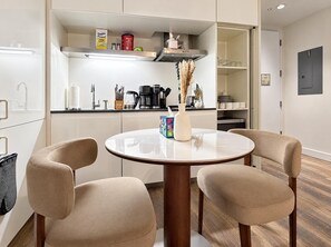 Una cocina moderna con una mesa redonda, dos sillas y diversos electrodomésticos.