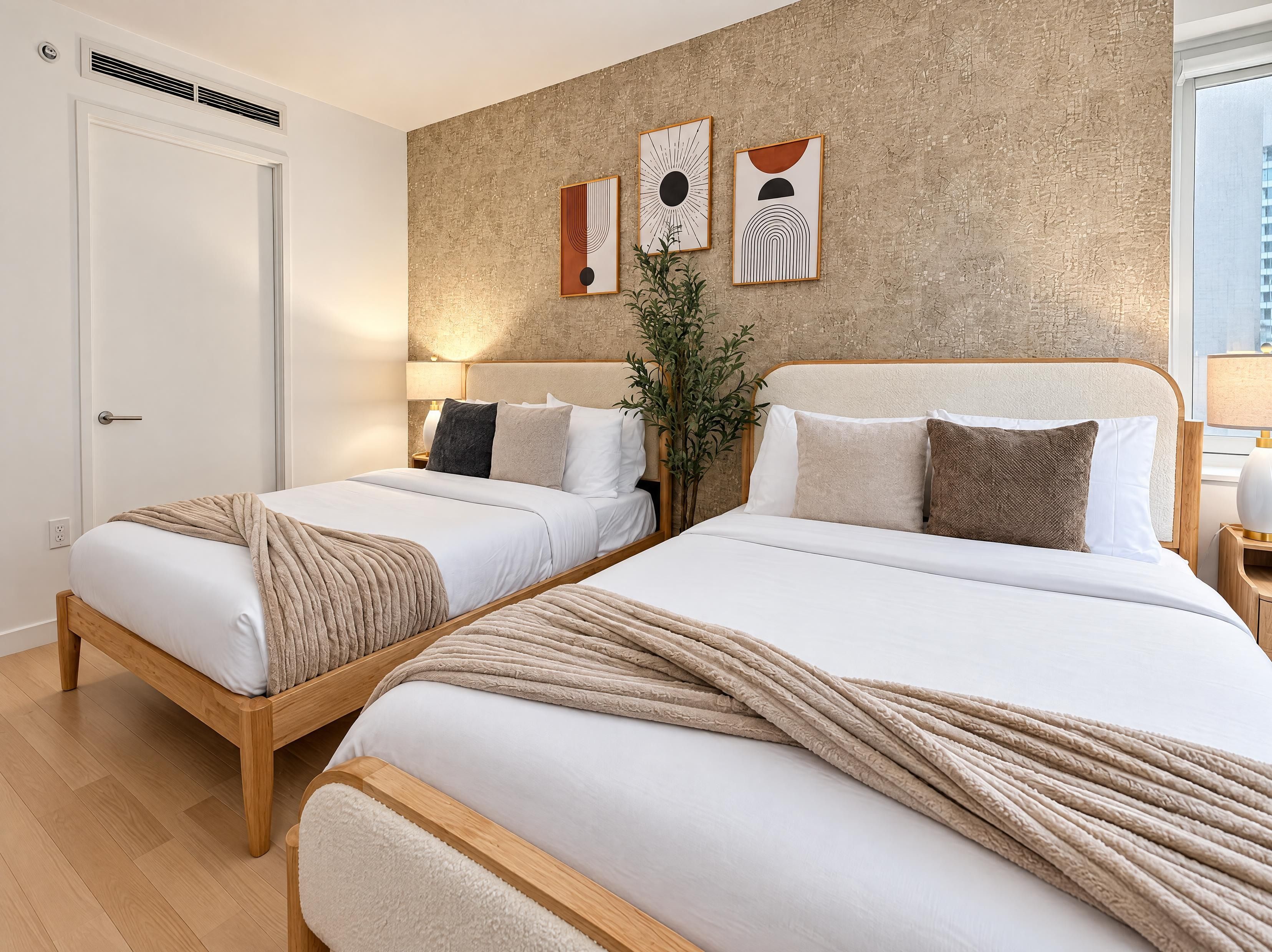 Ett hotellrum med två sängar, en vägg med en intressant yta och konstverk.