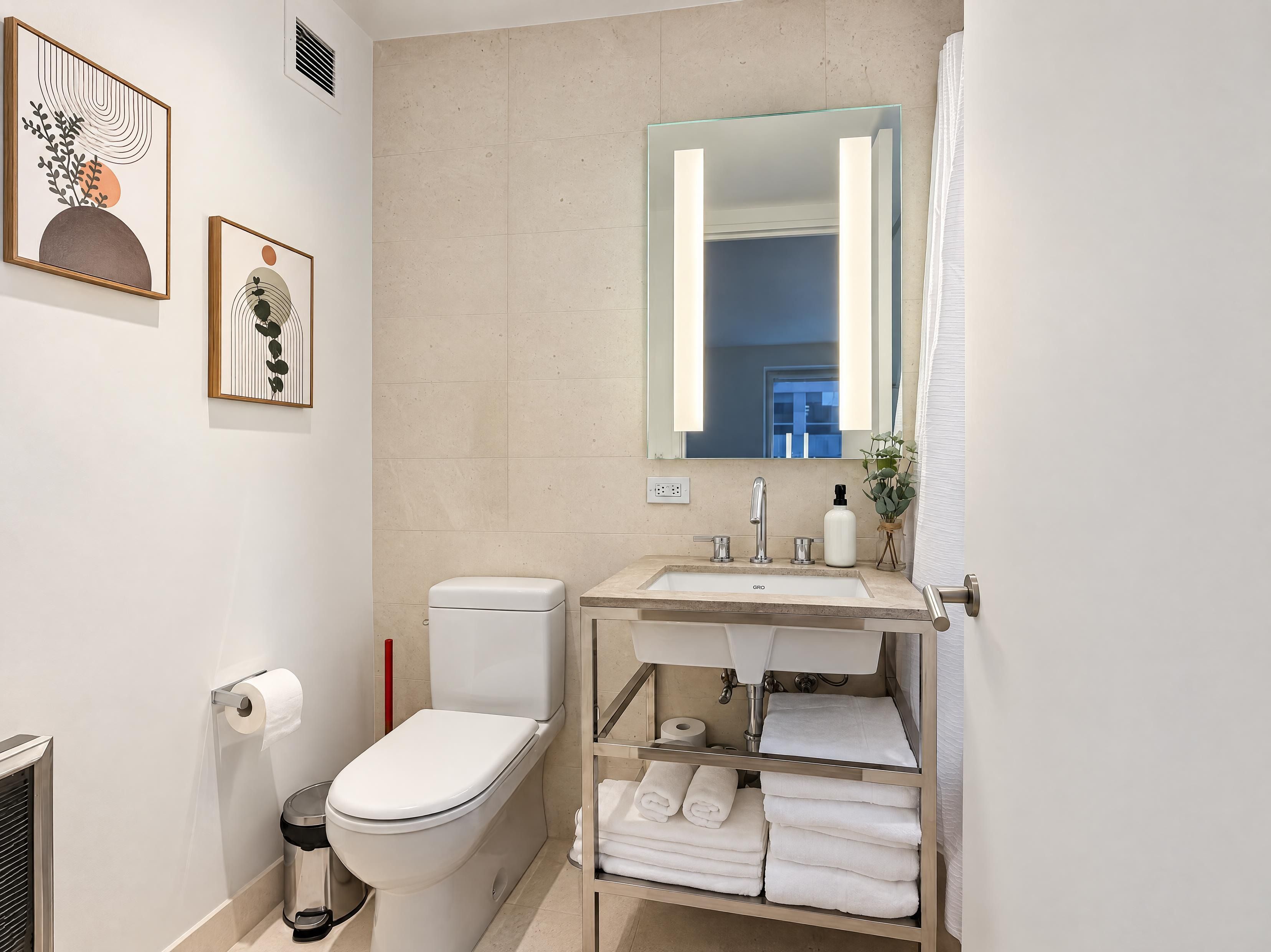 Un baño moderno con inodoro, lavamanos y perchero para toallas.