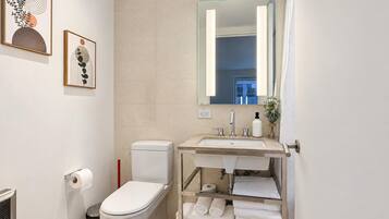Un baño moderno con inodoro, lavamanos y perchero para toallas.