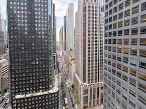 A high-rise urban building with a grid of windows, a central courtyard, and a street with vehicles and pedestrians.