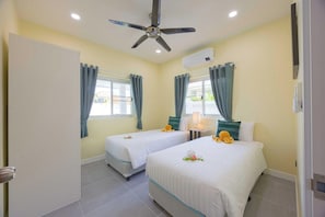 Habitación de hotel con dos camas, ventilador de techo, aire acondicionado y ventana con cortinas.