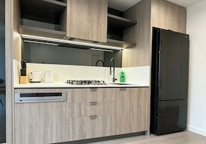 Eine moderne Küche mit eingebautem Geschirrspüler, einem schwarzen Kühlschrank und einem Gasherd.