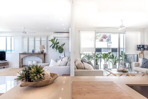 A modern living room with a fireplace, sofas, and a coffee table. - Sunshine Luxe Penthouse - Wide Ocean Views (Sunshine Beach)