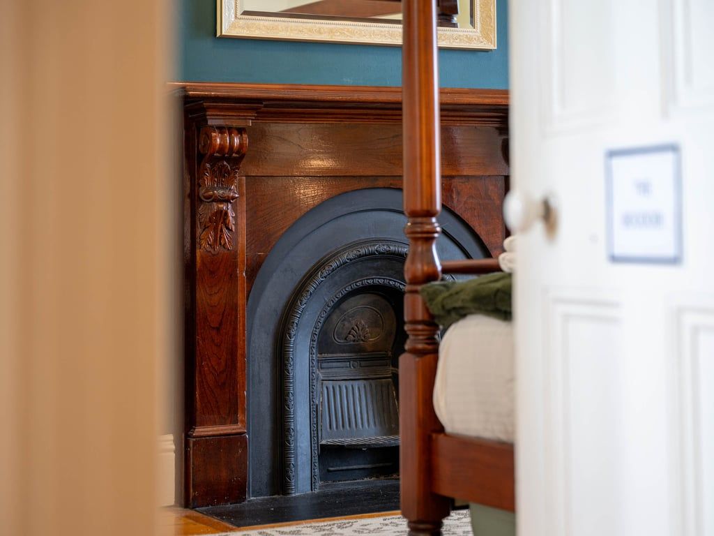 A room with a wooden fireplace, a white door, and a patterned rug.