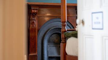 A room with a wooden fireplace, a white door, and a patterned rug.