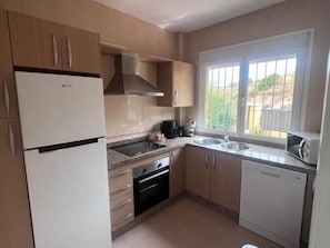 A compact kitchen with a refrigerator, stove, sink, and dishwasher. - Townhouse with Year-Round Pool and Private Garage (Fuengirola)