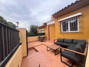 A covered patio area with a sofa, chairs, and a small table. - Townhouse with Year-Round Pool and Private Garage (Fuengirola)