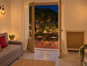 An open doorway leading to an outdoor patio with a table and chairs, a sofa with a red pillow inside, and a wall-mounted light fixture. - Renovated Two-Bedroom Apartment with Two Terraces and Sea Views (Benalmádena)