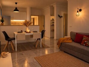 Un salon moderne avec un coin repas, un canapé et une cuisine en arrière-plan.