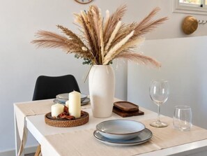A dining table set with plates, candles, a vase with dried pampas grass, and a wine glass. - Renovated Two-Bedroom Apartment with Two Terraces and Sea Views (Benalmádena)