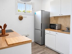 A compact kitchen with a refrigerator, microwave, and wooden countertop. - Renovated Two-Bedroom Apartment with Two Terraces and Sea Views (Benalmádena)