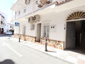 A building with a stone facade, a balcony, and a door with a decorative arch. - Studio with Patio in Central Arroyo de la Miel (Benalmádena)