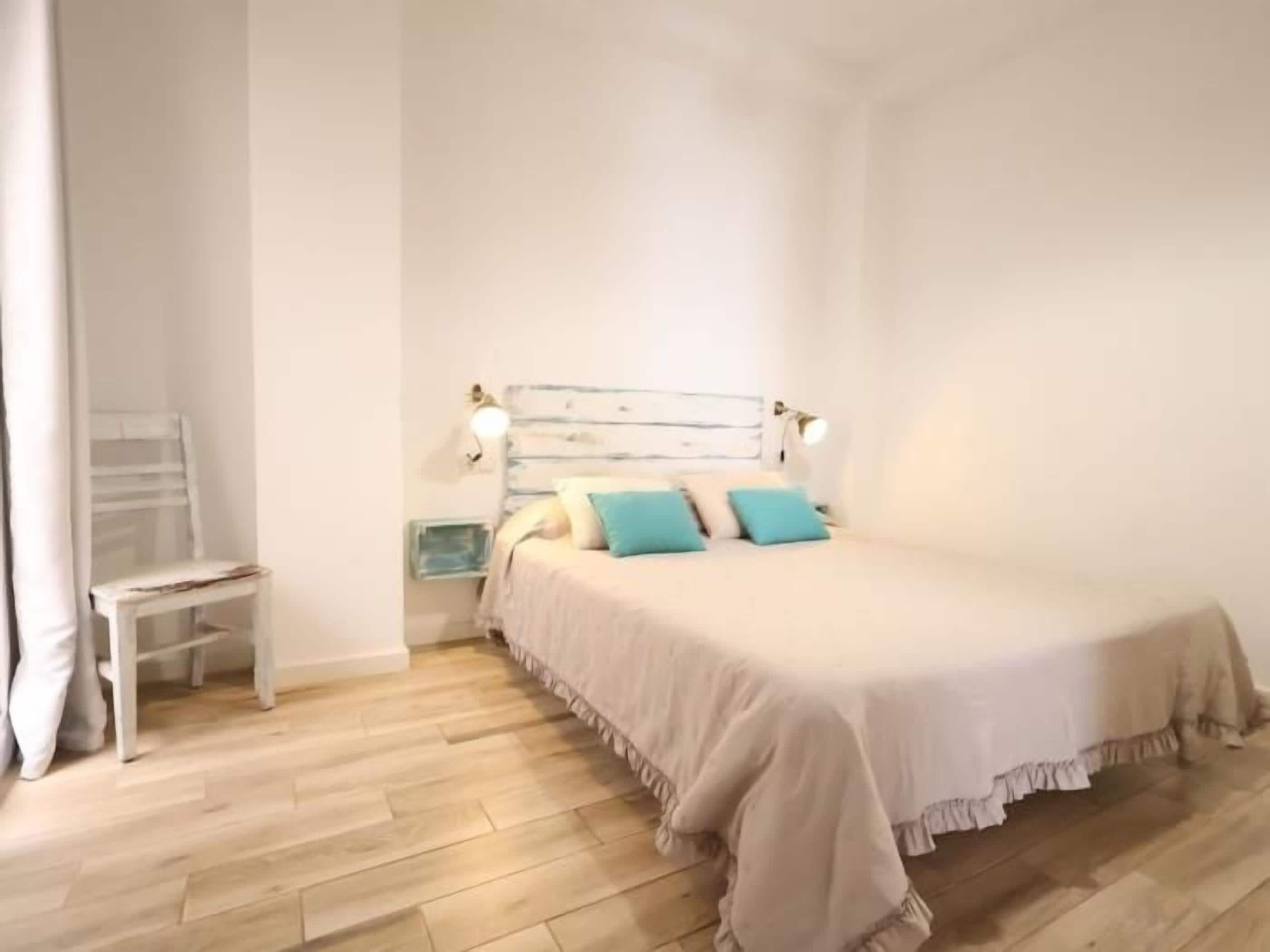 A bedroom with a bed, bedside tables, and a chair.