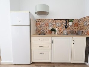 Eine Küche mit einem weißen Kühlschrank, einer Spüle und einer gefliesten Rückwand.