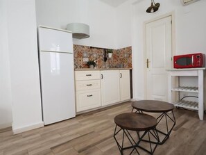 Eine kompakte Küche mit Kühlschrank, Schränken, einer Mikrowelle und einem kleinen Esstisch.