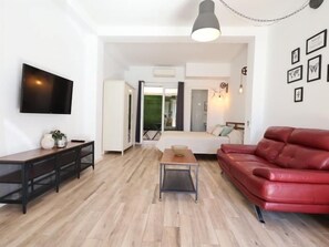 A modern living room with a flat-screen TV, a red leather sofa, and a wooden coffee table. - Studio with Private Patio in Arroyo de la Miel (Benalmádena)