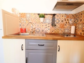 Een keuken met een houten aanrecht, een spoelbak en een decoratieve spatwand.