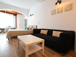 Een moderne slaapkamer met een bed, een zwarte bank, een witte tafel en een houten vloer.
