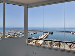 Blick aus einem Fenster auf einen Jachthafen mit Booten und blauem Himmel.