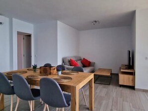 Una sala de estar moderna con una mesa de comedor, sillas, un sofá y un televisor.