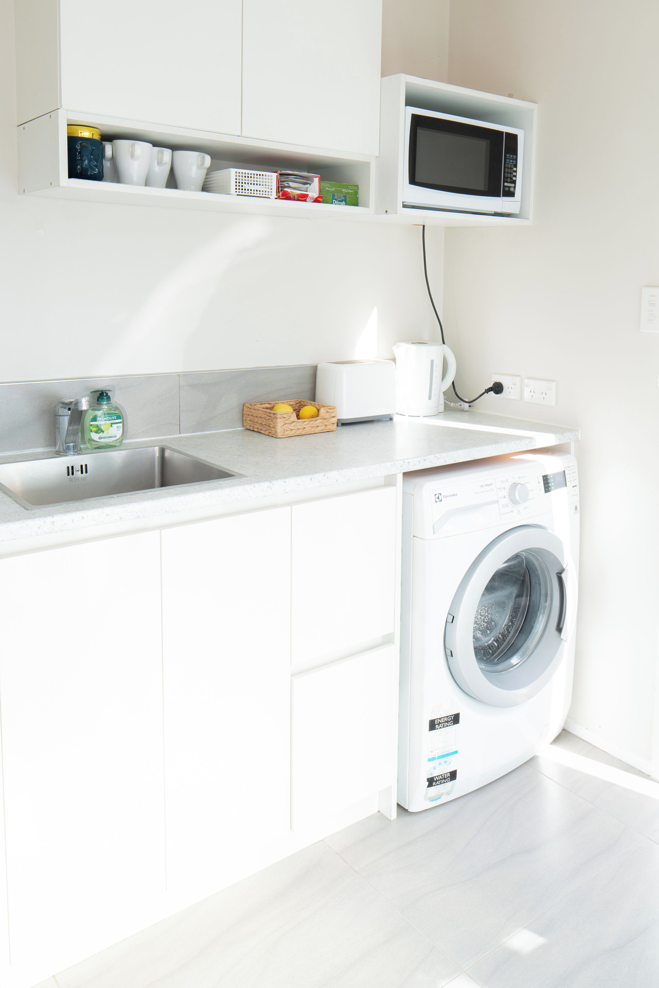 A modern kitchen with a built-in washing machine, a microwave, and a sink.