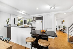 Cozinha moderna com ilha central, banquetas e mesa de jantar.