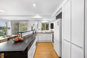 Cozinha moderna com armários brancos, bancada preta e piso de madeira.