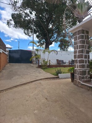 A paved driveway leading to a building with a stone pillar and a covered area with outdoor furniture. - Cozy villa with a pool, 5 minutes from the airport, close to all amenities (Talatamaty)