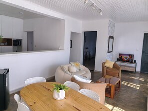 A modern living room with a wooden dining table, white chairs, a beige sofa, and a brown armchair. - Cozy villa with a pool, 5 minutes from the airport and close to all amenities (Talatamaty)