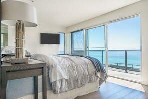 A bedroom with a large bed, a bedside table, a lamp, a flat-screen TV, and a balcony with a view of the sea. - Dromana Relaxation Escape by Ready Set Stay- Positioned on a cliff & WiFi (Dromana)