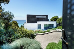 A modern two-story house with a white facade, a dark roof, and a view of the sea. - Dromana Relaxation Escape by Ready Set Stay- Positioned on a cliff & WiFi (Dromana)