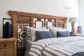A bedroom with a wooden headboard, a striped bedspread, and a bedside table with a lamp. - Dromana Relaxation Escape by Ready Set Stay- Positioned on a cliff & WiFi (Dromana)