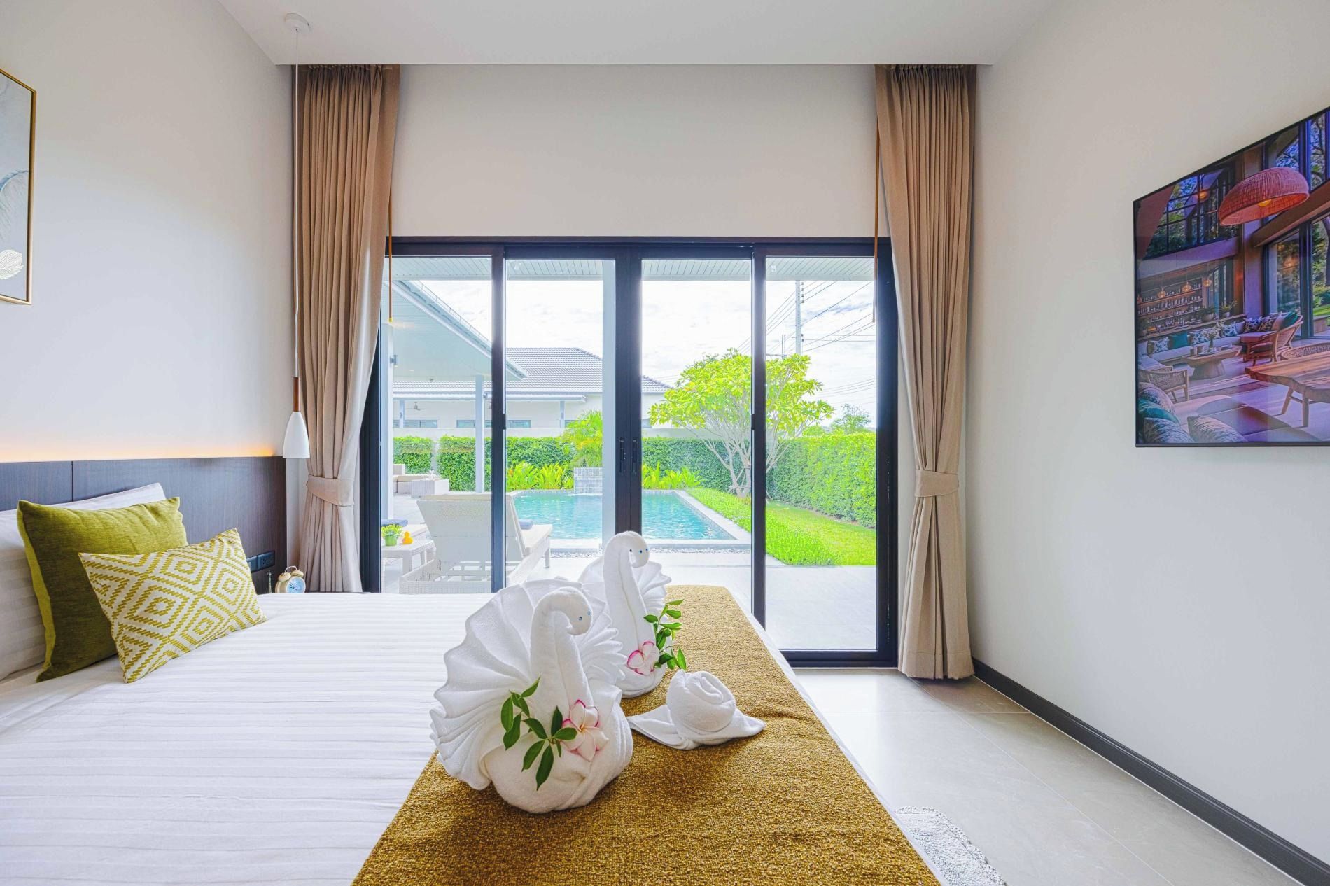 Habitación de hotel con una cama, un ventanal y vistas a una piscina y zonas verdes.
