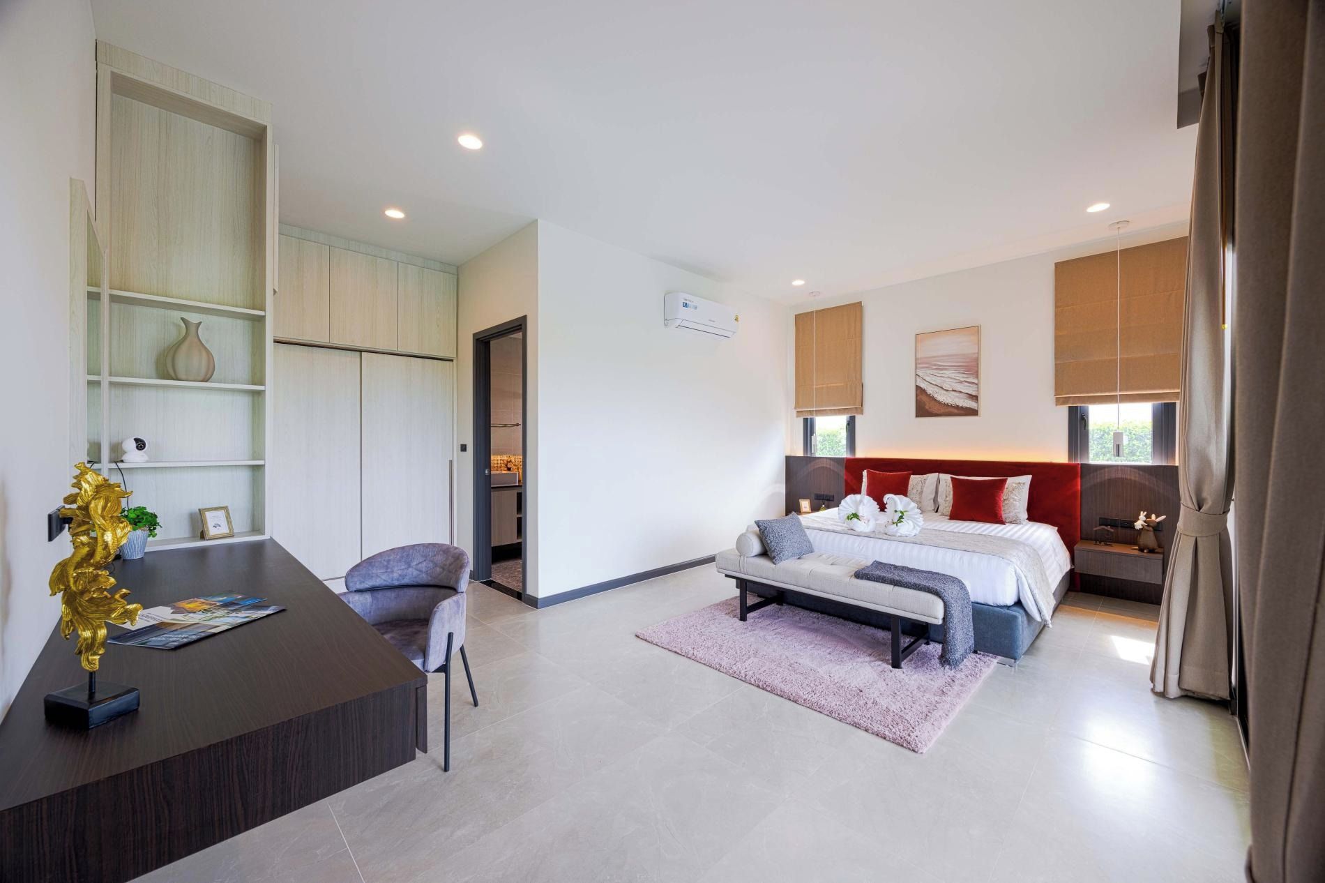 Quarto de hotel moderno com cama, escrivaninha e cadeira. Há uma janela grande com cortinas, ar condicionado na parede e um quadro na parede.