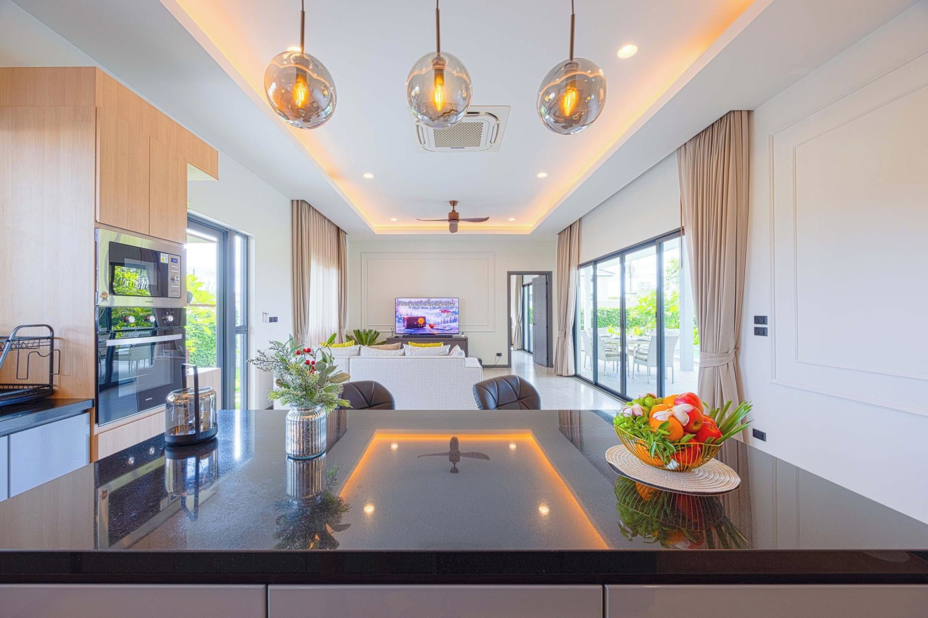 Una cocina moderna con una isla central, horno empotrado y un comedor con televisor.